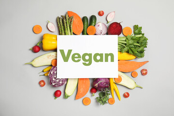 Paper card with word Vegan and fresh vegetables on white background, flat lay