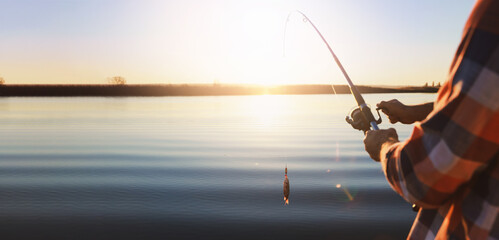 Fisherman catching fish with rod at riverside, closeup view with space for text. Banner design
