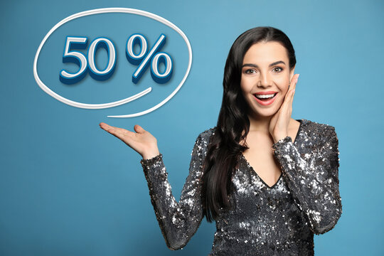 Surprised woman pointing at illustration of fifty percent on light blue background. Special promotion