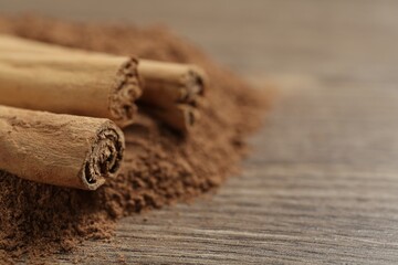Cinnamon powder and sticks on wooden table, closeup. Space for text