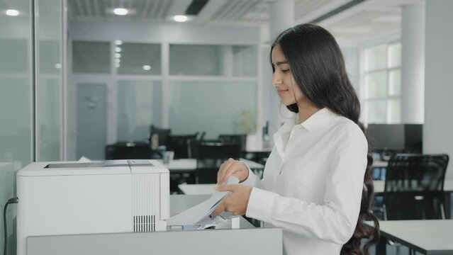 Arab hispanic businesswoman girl worker secretary makes copies on photocopier use office equipment print machine replicate papers sending fax printing document press buttons on multifunctional printer