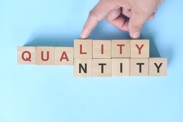 Quality over quantity concept. Hand changing word quantity to quality on wooden blocks. - obrazy, fototapety, plakaty