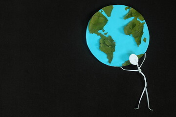 Human stick figure man carrying the earth on his shoulders on dark black background. Save planet...