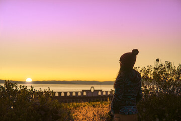 Woman enjoying the sunrise with a view from the alto Sancayuni stadium of the Amantaní island, Titicaca lake