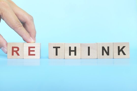 Rethink and reevaluate in business concept. Hand changing word think to rethink on wooden blocks.