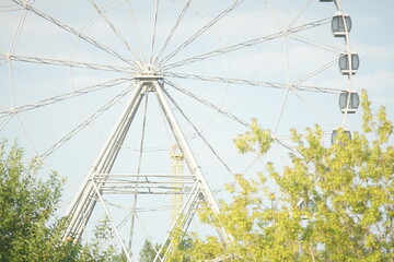 Obraz premium Horizontal full-color photo. Urban landscape. Geometric semicircular composition. The attraction is a Ferris wheel.