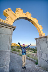 Fototapeta na wymiar woman in triumphal pose, arriving at the sun arch, illuminated by the first rays of the sun, on Amantani Island, Lake Titicaca.