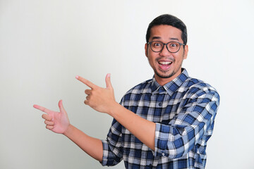 Adult Asian man showing excited expression while pointing to the right side