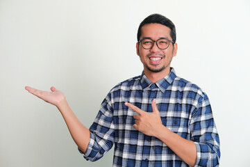 Adult Asian man smiling with left hand pointing to his opened right hand palm