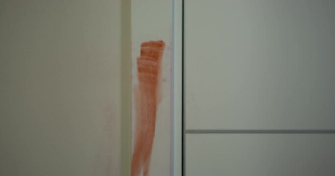 Hungry creepy zombie killed by a shot slowly slides down the wall leaving a bloody trail on it