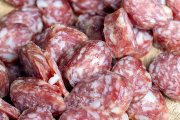sliced thin sausage with bacon on a wooden dish
