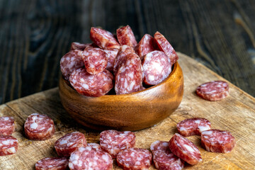 sliced thin sausage with bacon on a wooden dish