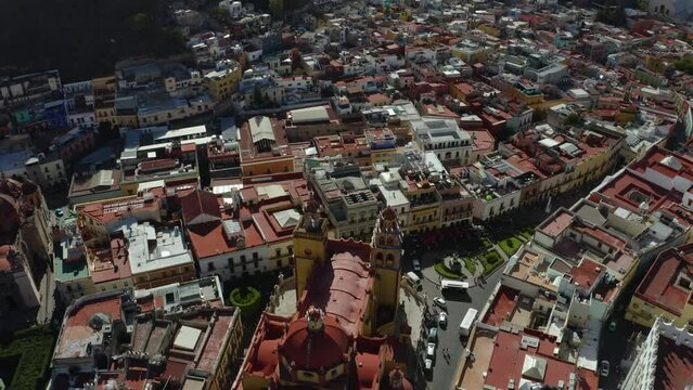 Aerial bird's eye shot over Taxco de Alarcon city along Santa Prisca Parish Church in Guerrero state, Mexico on a bright sunny day.
