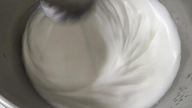 Commercial heavy duty electric mixer mixing and whipping egg white until peak, preparation for fluffy and airy Swiss meringue buttercream, close up shot.