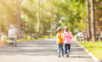 a boy and a girl are enthusiastically talking about something while walking in the park