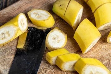 not peeled ripe yellow banana cut into pieces on a board