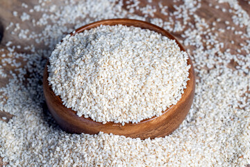 a large amount of white dried sesame seeds in a wooden bowl