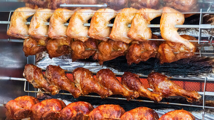 Tasty chicken, chicken legs and turkey drumsticks on a rotisserie in the restaurant