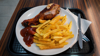 Tasty turkey drumsticks with French fries and ketchup in the street restaurant