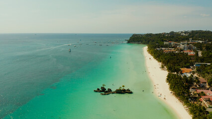 White sand beach and Willy's rock with tourists and hotels and sailing boat on Boracay Island. Aerial drone: Tropical white beach with sailing boat. Summer and travel vacation concept.