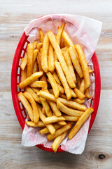 Red basket with delicious french fries on a wooden table
