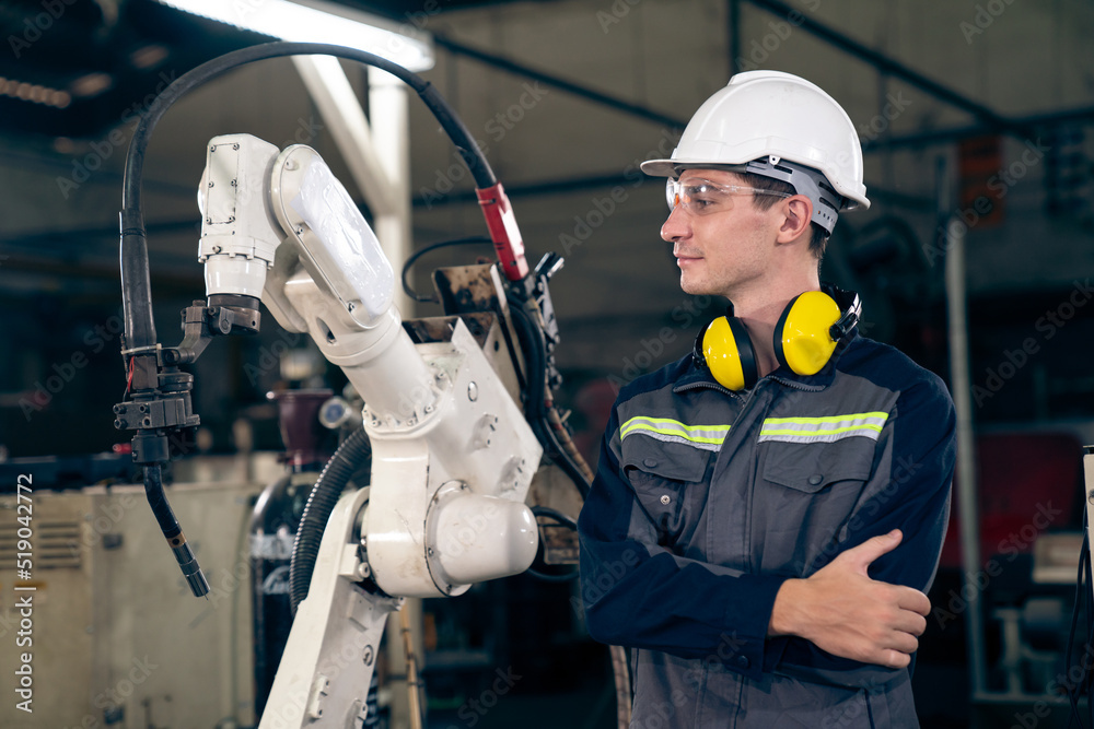 Poster young factory worker working with adept robotic arm in a workshop . industry robot programming softw