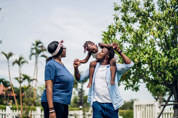 Portrait of enjoy happy love black family african american father and mother with little african girl child smiling and play having fun moments good time in park at home