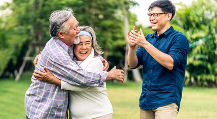 Portrait enjoy happy smiling love multi-generation asian big hug family.Senior mature father and elderly mother with young adult man son outdoor in park at home.insurance concept