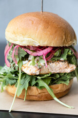 Grilled salmon burger with cheese, tomato, arugula and onions