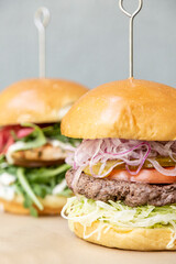 Grilled salmon burger with red onion, tomato and arugula and beef burger with cheese, onion, tomato and lettuce.