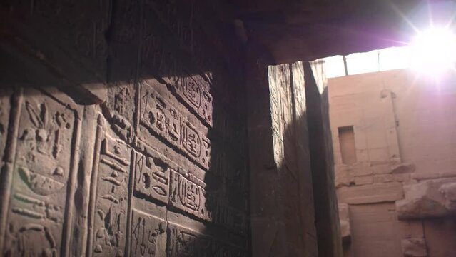 Close detail of sunrays hitting hieroglyphs on the walls inside the temple of Philae, Aswan, Egypt.