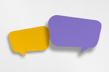 Purple and yellow paper cut speech balloon shapes isolated on white paper background.