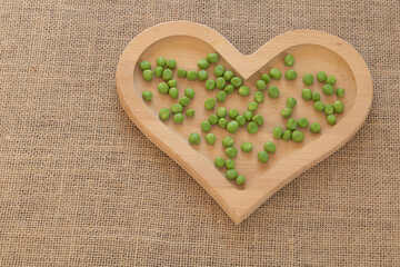 Close up shot of green peas on a wooden heart plate