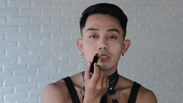 A bisexual guy paints his lips and looks passionately into the camera. A transgender man has the right to be inclusive and to be free of self-identity. The concept of lgbt community in the world.