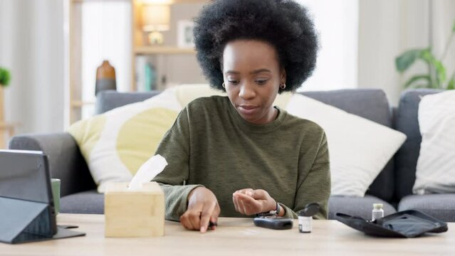 Black woman doing glucose monitoring at home. Smiling African American female using a blood sugar measuring device in a living room. Daily routine of a diabetic with a rapid home result testing kit