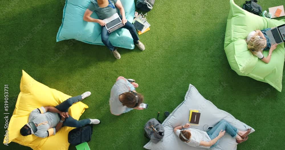 Poster Above view of students using modern technology and sitting on bean bags at campus. Futuristic and trendy startup to improve creativity and mindfulness. Spot for staff to relax and browse the internet