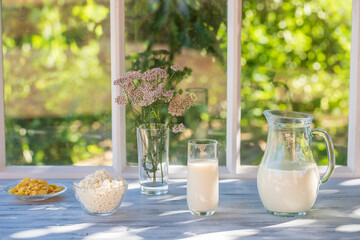 Milk in a jug in a glass and cottage cheese on the windowsill by the window of the house on a...