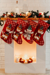 Four Christmas red socks hanging on white fireplace in room.