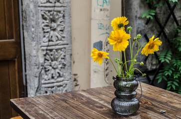 Yellow flowers in a vase on the background of the decor of the ancient city.