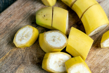 not peeled ripe yellow banana cut into pieces on a board