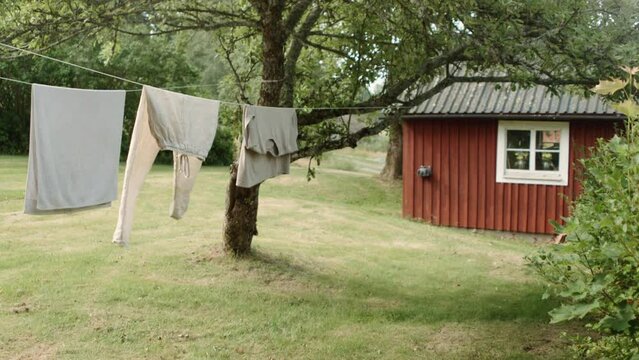 Laundry drying in the sun on drying line in front of swedish farmhouse