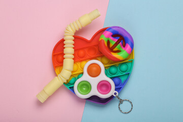 Different antistress toys on pink blue pastel background. Pop it, pop tube, snapperz, simple dimple. Flat lay.Top view