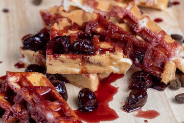 soft waffles with red cherry jam on a serving board