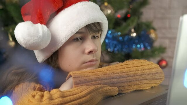 Festive child Christmas by notebook. A sad girl watch the notebook during festive Christmas night in the room.
