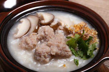 Pork porridge with shiitake mushrooms in brown cups topped with coriander and fried garlic
