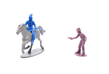 Wild West. Plastic figurines of a cowboy and a native american on a horse exchange fire on a white...