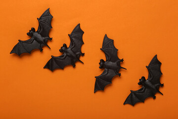 Plastic bats on orange background. Halloween decor. Top view
