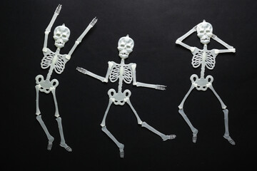 Three funny dolls dancing skeletons on a black background. Halloween background