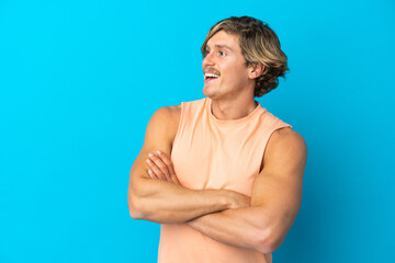 Handsome blonde man isolated on blue background happy and smiling