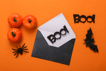 Halloween black envelope with words boo! and halloween decor on orange background. Creative layout....